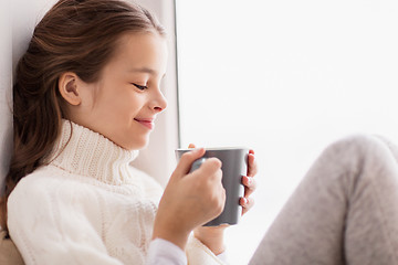 Image showing girl with tea mug sitting at home window