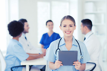 Image showing happy doctor with tablet pc over team at clinic