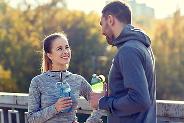 Image showing smiling couple with bottles of water outdoors