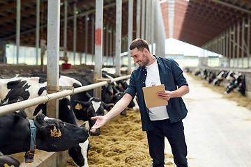 Image showing farmer with clipboard and cows in cowshed on farm