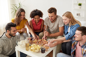 Image showing happy friends with drinks eating pizza at home