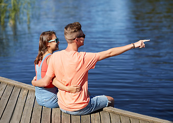 Image showing happy couple pointing finger on summer river berth