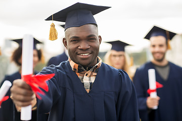 Image showing happy students in mortar boards with diplomas