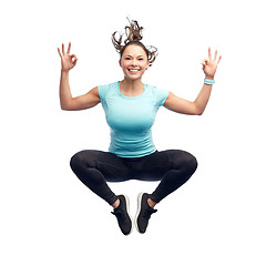 Image showing happy smiling sporty young woman jumping in air