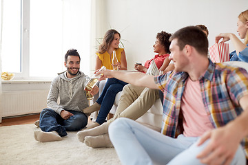 Image showing group of happy friends with drinks talking at home