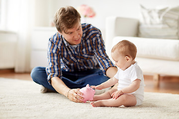 Image showing happy father with baby and piggy bank at home