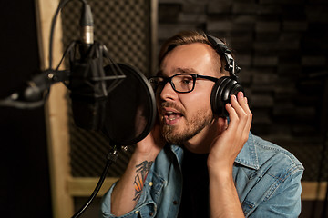 Image showing man with headphones singing at recording studio