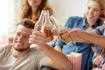 Image showing happy friends clinking beer bottles at home party