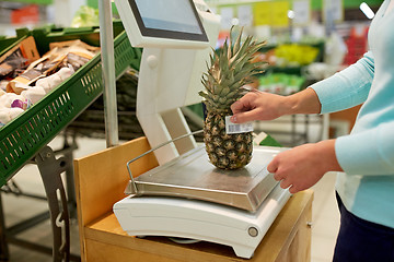 Image showing woman weighing pineapple on scale at grocery store