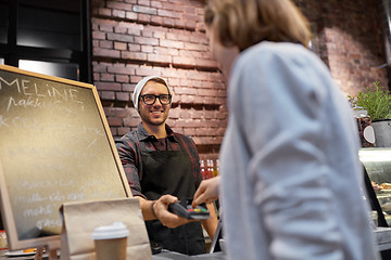 Image showing happy woman paying for purchases at cafe