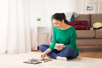 Image showing happy woman with money and travel map at home