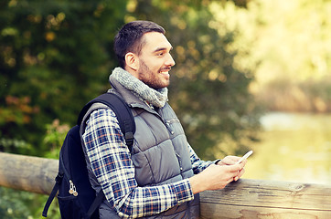 Image showing happy man with backpack and smartphone outdoors