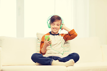 Image showing happy boy with smartphone and headphones at home