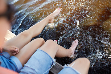 Image showing legs of young couple sitting on river berth