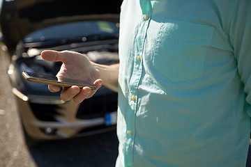 Image showing close up of man with smartphone and broken car