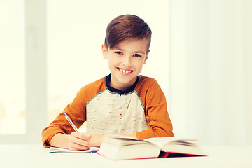 Image showing smiling student boy writing to notebook at home