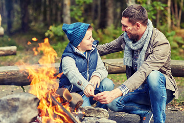Image showing father and son roasting marshmallow over campfire