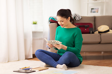 Image showing happy woman with money and travel map at home