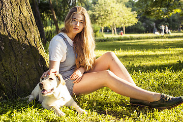 Image showing young attractive blond woman playing with her dog in green park at summer, lifestyle people concept