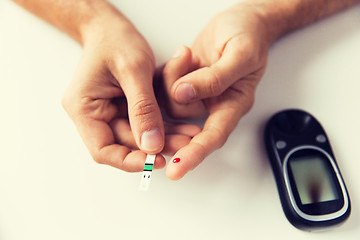 Image showing close up of man checking blood sugar by glucometer