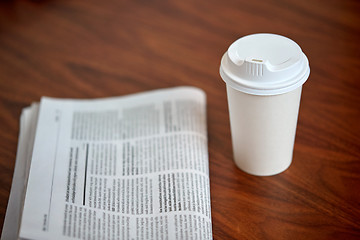 Image showing coffee drink in paper cup and newspaper on table