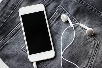 Image showing smartphone and earphones on denim or jeans pocket