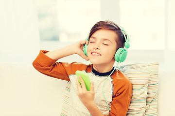 Image showing happy boy with smartphone and headphones at home