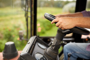 Image showing senior man driving tractor at farm