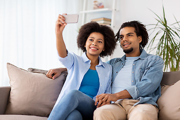 Image showing happy couple with smartphone taking selfie at home