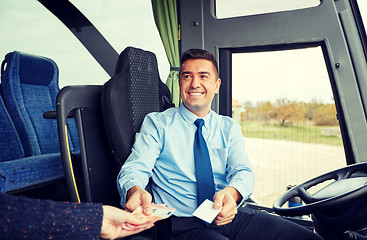 Image showing bus driver with money selling ticket to passenger