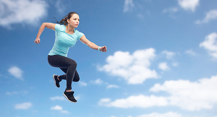 Image showing happy sporty young woman jumping in air