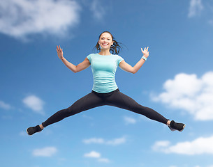 Image showing happy smiling sporty young woman jumping in air