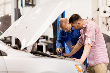 Image showing auto mechanic with clipboard and man at car shop