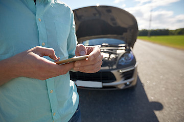 Image showing close up of man with smartphone and broken car