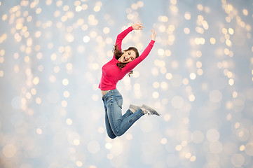 Image showing happy young woman jumping or dancing over lights