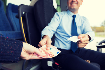 Image showing close up of bus driver selling ticket to passenger