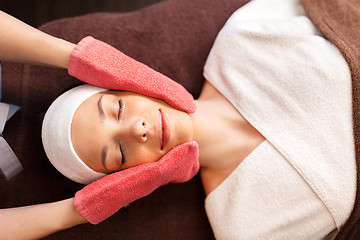 Image showing woman having face massage with terry gloves at spa