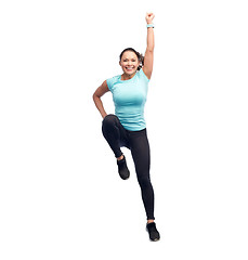 Image showing happy smiling sporty young woman jumping in air