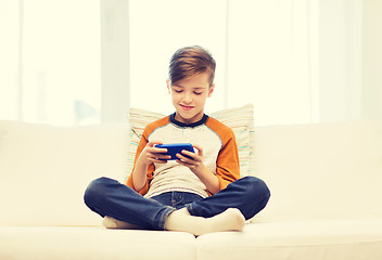 Image showing boy with smartphone texting or playing at home