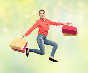 Image showing smiling young woman with shopping bags jumping