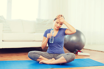 Image showing tired woman drinking water after workout at home