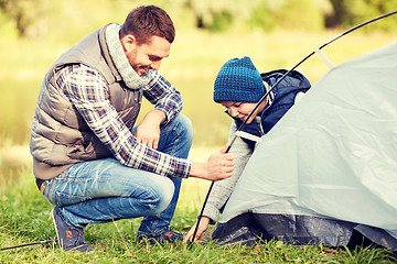 Image showing happy father and son setting up tent outdoors