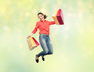 Image showing smiling young woman with shopping bags jumping