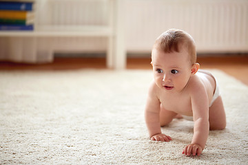 Image showing little baby in diaper crawling on floor at home
