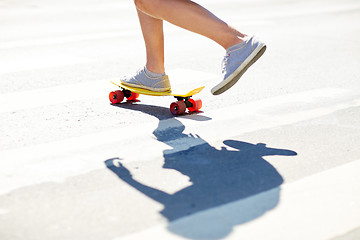 Image showing male legs riding short skateboard along crosswalk