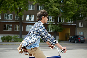 Image showing young hipster man with bag riding fixed gear bike