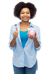 Image showing happy woman with piggy bank showing thumbs up