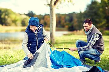 Image showing happy father and son setting up tent outdoors