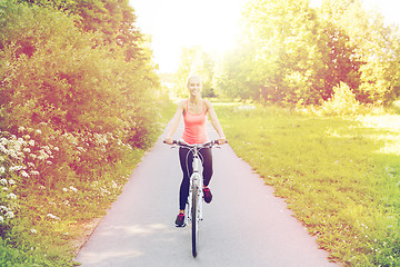 Image showing happy young woman riding bicycle outdoors