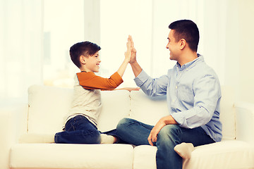 Image showing happy father and son doing high five at home